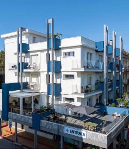 a white building with a balcony and an umbrella at Lilium Maris Hotel in Bibione