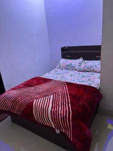 a bed with a red comforter in a room at Hotel Dausa Place in Dausa