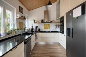 a large kitchen with white cabinets and black appliances at CasaRica Retreat in Charneca