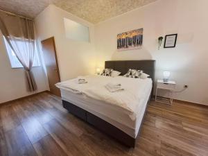 a bedroom with a large white bed and wooden floors at Apartments ATM in Šibenik +47 photos