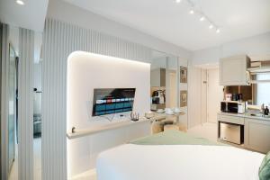a white bedroom with a television on a wall at Yoonah at Benson Pakuwon Mall in Lontar