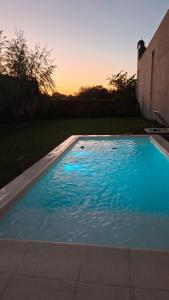 a blue swimming pool with a sunset in the background at Chacra Arcoiris in Gualeguay