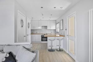 a kitchen with white cabinets and a gray couch at Finest Retreats - Bownder House in Cawsand