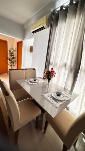 a table and chairs with a vase of flowers on it at Brisas do Lago 2 Quartos in Palmas