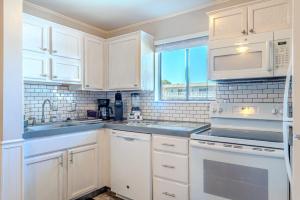 a white kitchen with white appliances and a window at Resort Retreat - Multiple Pools - Beach Access in Hilton Head Island +51 photos