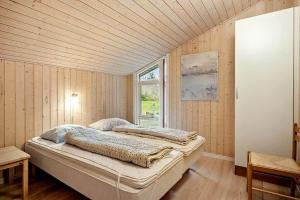two beds in a room with wooden walls and a window at JB406-Fjerritslev-Aspevej-68 in Fjerritslev
