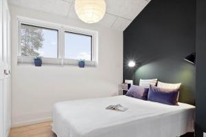 a bedroom with a white bed and two windows at 20514-Samso-Plantagevej-17 in Sælvig