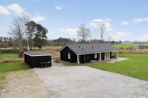 a small black house in a field at 20514-Samso-Plantagevej-17 in Sælvig