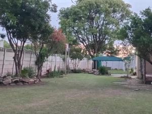 a yard with a fence and trees and a gate at taoana guesthouse in Kroonstad