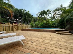 a wooden deck with a swimming pool and two benches at Le MORNE Aux F0US Cabanes & Jardin Tropical in Deshaies