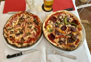 two pizzas sitting on plates on a table at Lodge Mini-Wood in Les Rochettes