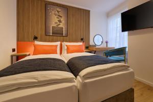 a bedroom with a large bed with orange pillows at Franziskaner by Centra in Zurich +29 photos