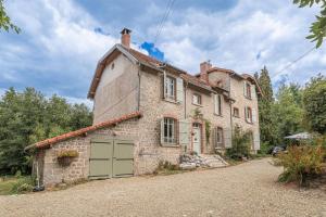 an old stone house with a green garage at Bon Chez Nous in Saint-Amand-Jartoudeix