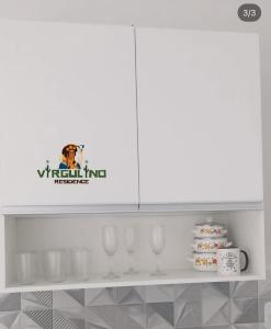 a white shelf with glasses and a sign on it at Virgulino Residence in Piranhas