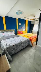 two beds in a bedroom with blue and yellow walls at Kitjamyhome1 in Hat Yai