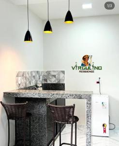 a kitchen with a counter with two stools at Virgulino Residence in Piranhas