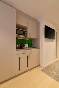 a kitchen with white cabinets and a flat screen tv at Franziskaner by Centra in Zurich