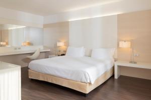 a bedroom with a large white bed and a desk at Laguna Palace Hotel Grado in Grado