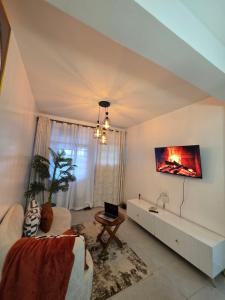 a living room with a couch and a tv on the wall at Rio Cabins in Nyeri