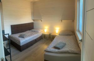 two beds in a small room with two lights at Domček in Budimír