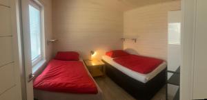 two beds in a small room with red sheets at Domček in Budimír +2 photos