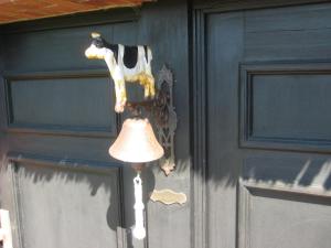 a cow figure on a bell next to a door at Ferienhaus von der Ahe in Mohrkirch +11 photos