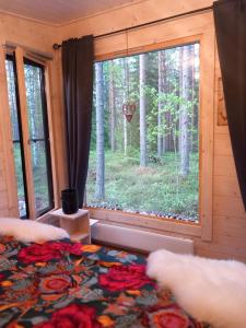 a bedroom with a large window in a forest at Nature resort Linnunrata in Oulu