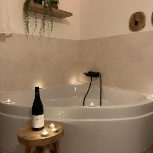 a bottle of wine sitting on a table next to a bath tub at Love room - Montélimar in Montélimar