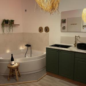a bathroom with a tub and a sink and a bottle of wine at Love room - Montélimar in Montélimar