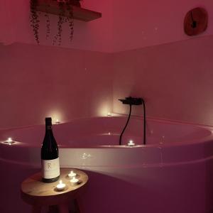 a bottle of wine sitting on a table next to a bath tub at Love room - Montélimar in Montélimar