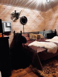 a bedroom with wooden walls and a bed with fur at Nature resort Linnunrata in Oulu