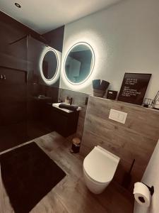 a bathroom with a toilet and a sink and two mirrors at Apartment Timeout in Welschbillig +23 photos