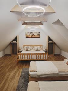 a attic bedroom with two beds and a chandelier at Ubytování Ve dvorku in Uherčice