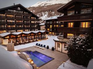 a resort with a swimming pool in the snow at Mirabeau Etoile in Zermatt