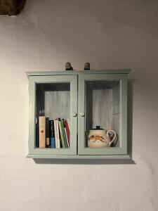 a green cabinet with a tea pot and books at La Casetta di Nonno Mario in Chiusdino