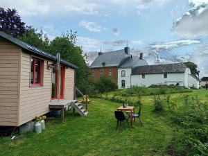 a yard with a house and a table and chairs at La roulotte Ô Cwèrbâs in Gouvy