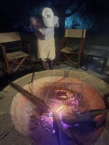 a man standing in front of a table with a fire pit at Mongwe Safari Camp in Nyakarura