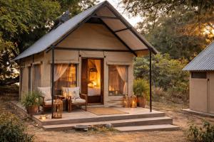 a small cabin with a porch in the woods at Mongwe Safari Camp in Nyakarura
