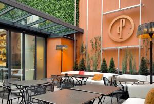 a restaurant with tables and chairs and a clock on the wall at Perpetual Elysée Montaigne in Paris
