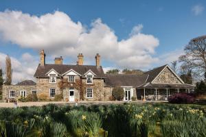 a large stone house with a garden in front of it at Tyddyn Llan Restaurant with Rooms in Corwen