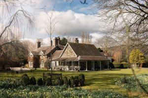 a large house on a lawn with flowers in front of it at Tyddyn Llan Restaurant with Rooms in Corwen +7 photos