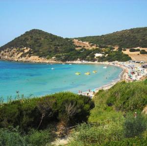 a beach with a bunch of people in the water at Su Ghindalu Guesthouse in Villanova Monteleone
