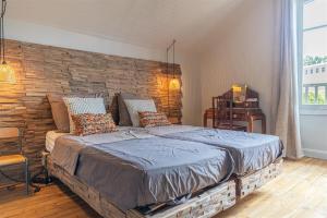 a bedroom with a large bed with a stone wall at Bon Chez Nous in Saint-Amand-Jartoudeix
