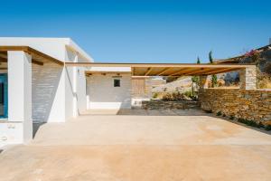 a patio with a stone wall and a wooden pergola at Sunset Heaven Villa on Kea in Korissia