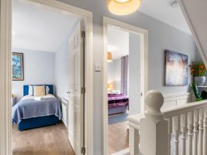 a bedroom with a bed and a hallway with a staircase at Pink Blossom in Clifden