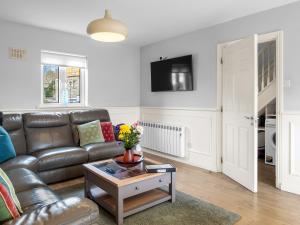a living room with a leather couch and a table at Pink Blossom in Clifden