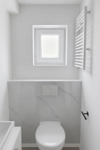 a white bathroom with a toilet and a window at My Loft in Hagen