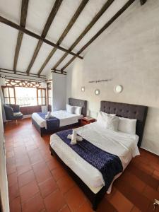 a bedroom with two beds and a chair at Apartamento de la Villa I in Villa de Leyva