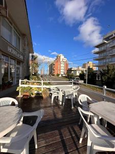 a group of white tables and chairs on a deck at Tamanacos Hotel & Spa in Villa Gesell
