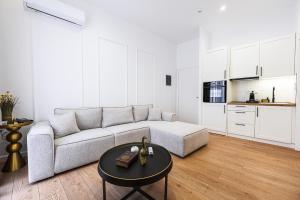 a white living room with a couch and a table at Lithos Boutique Residences in Volos